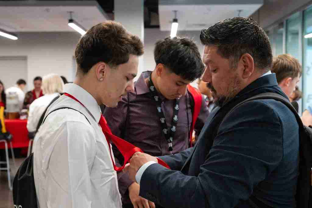 Rigo Garcia helps Future Leader Jason Slonaker tie his tie.